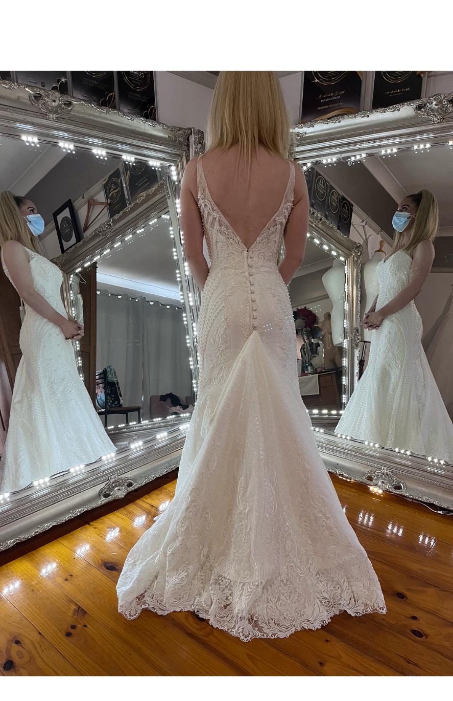 Bride in a fitted lace mermaid wedding gown with low V-back and covered button closure — hand stitched lace and beading resizing with bustle added by Jacqui