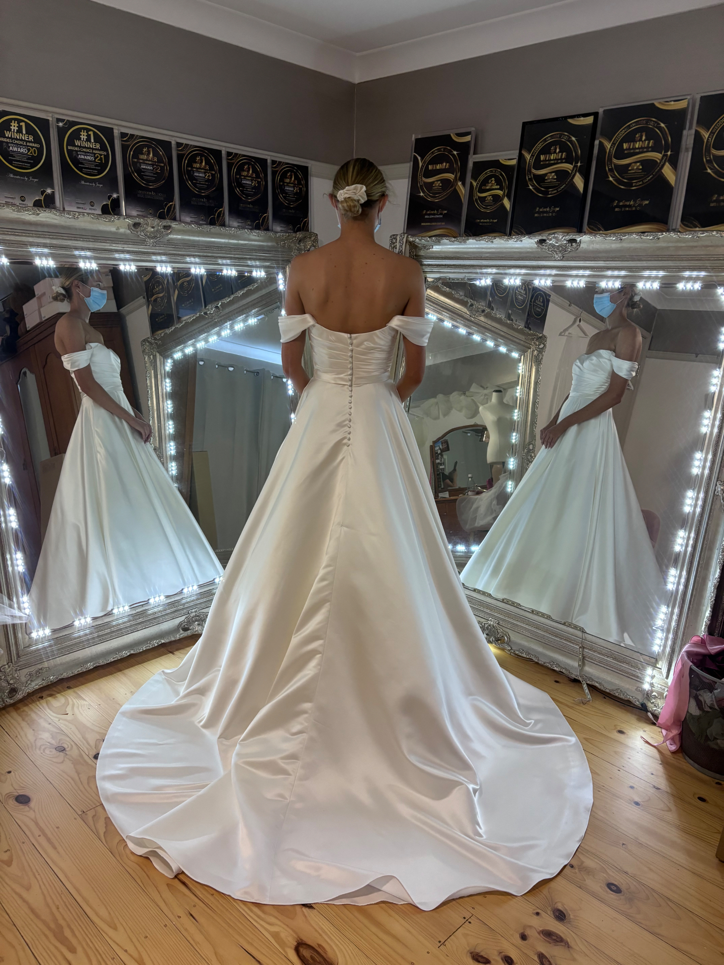 Bride from behind in an ivory satin off-shoulder ball gown with covered buttons and full chapel train — train steaming, alterations and hand crafted bustle by Jacqui